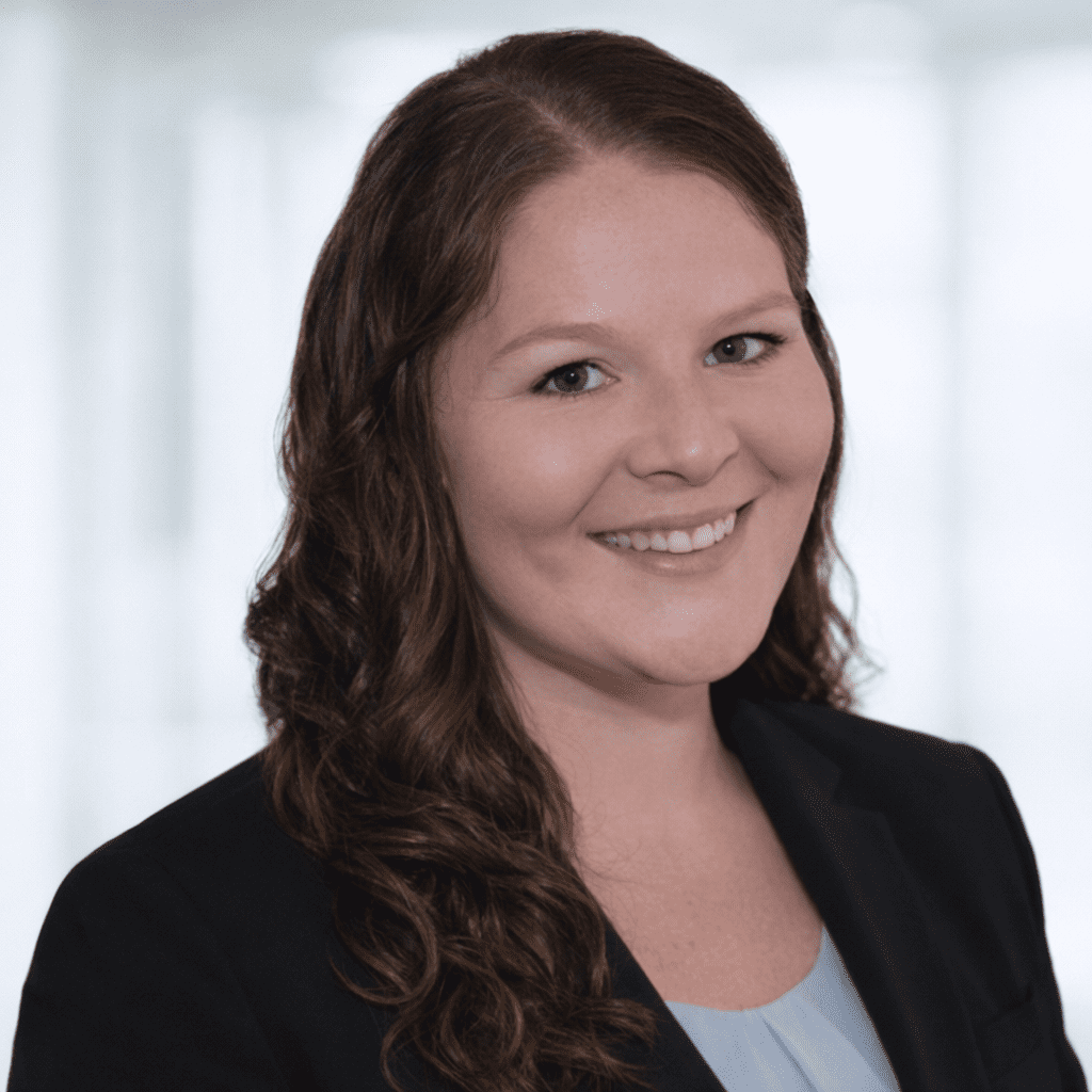 Professional headshot of a smiling woman with long brown hair.