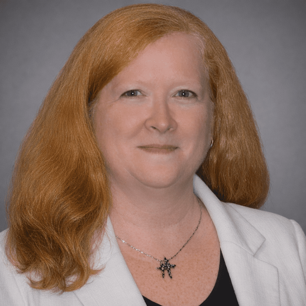 Professional woman with red hair and a white blazer.